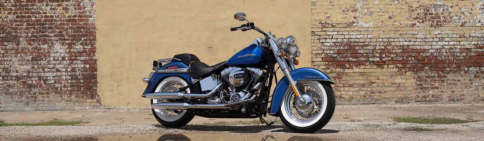 A shiny blue motorcycle parked before a brick wall.